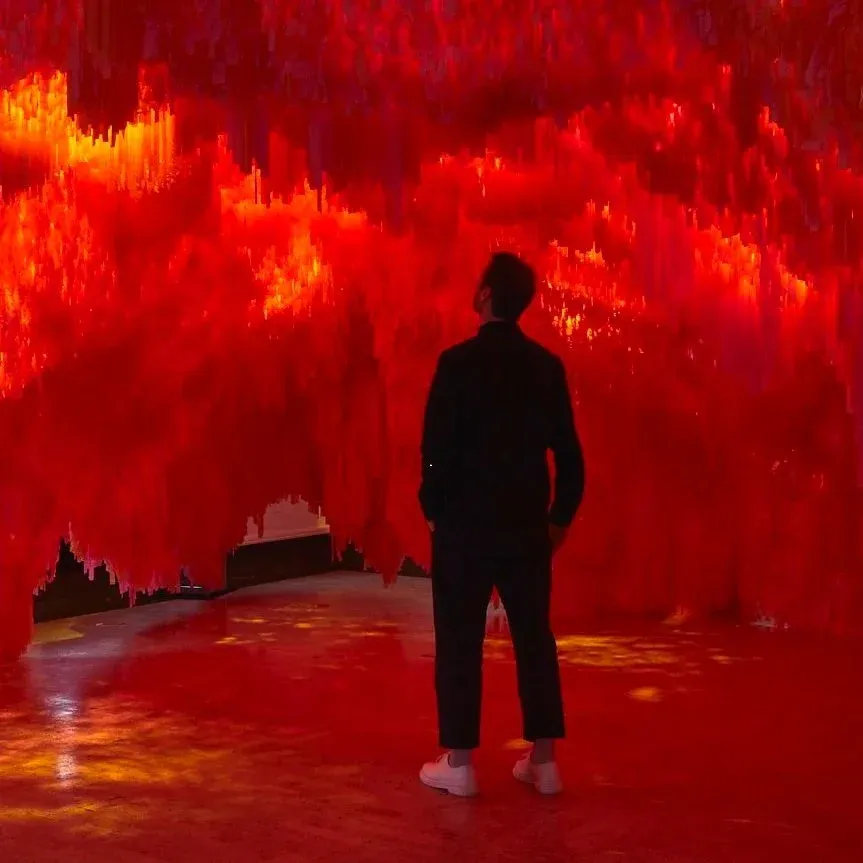 A visitor inside Bloom Bloom, a colorful cave-like installation